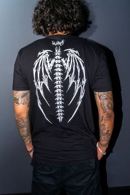 A man viewed from behind wearing the Riddim Fallen Angel t-shirt with a large white winged spine graphic on the back, and "WRH" printed in barbed text above it set against a dark gray background.